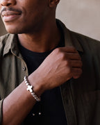 Close-up of the silver Atlas Cross Bead Bracelet worn by a man, shown at true size
