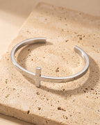 Silver Atlas cross cuff bracelet on warm stone