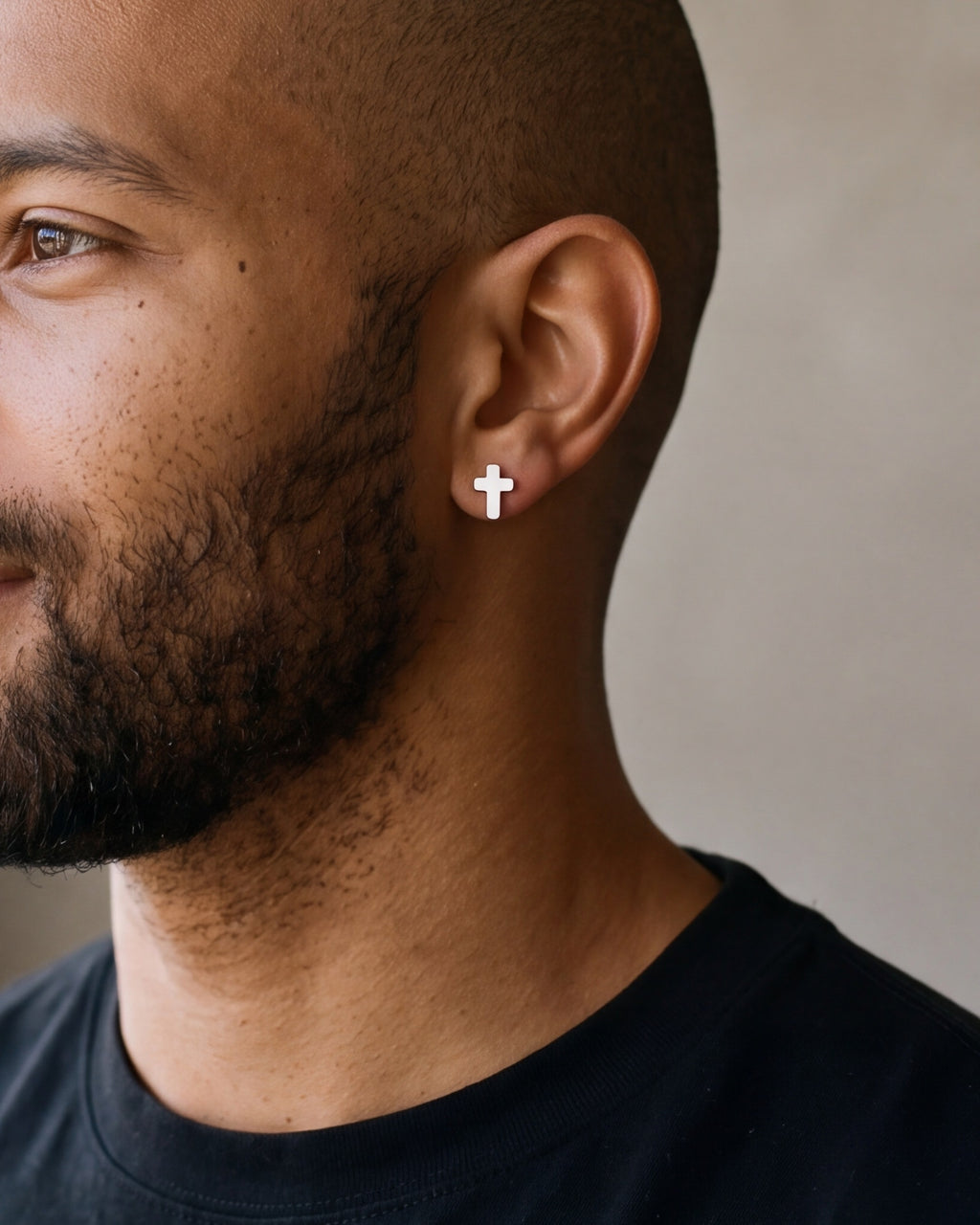 Close-up of the Atlas cross stud earrings in silver-tone steel, worn at true size