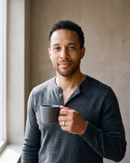 Man in a fine-gauge charcoal-grey merino knit with a henley neckline wearing the gold-tone Atlas Crosshatch Inlay Dome Ring
