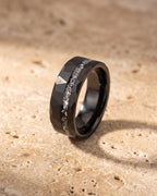 Entire Atlas crushed metal inlay ring in black steel, lying flat on warm stone