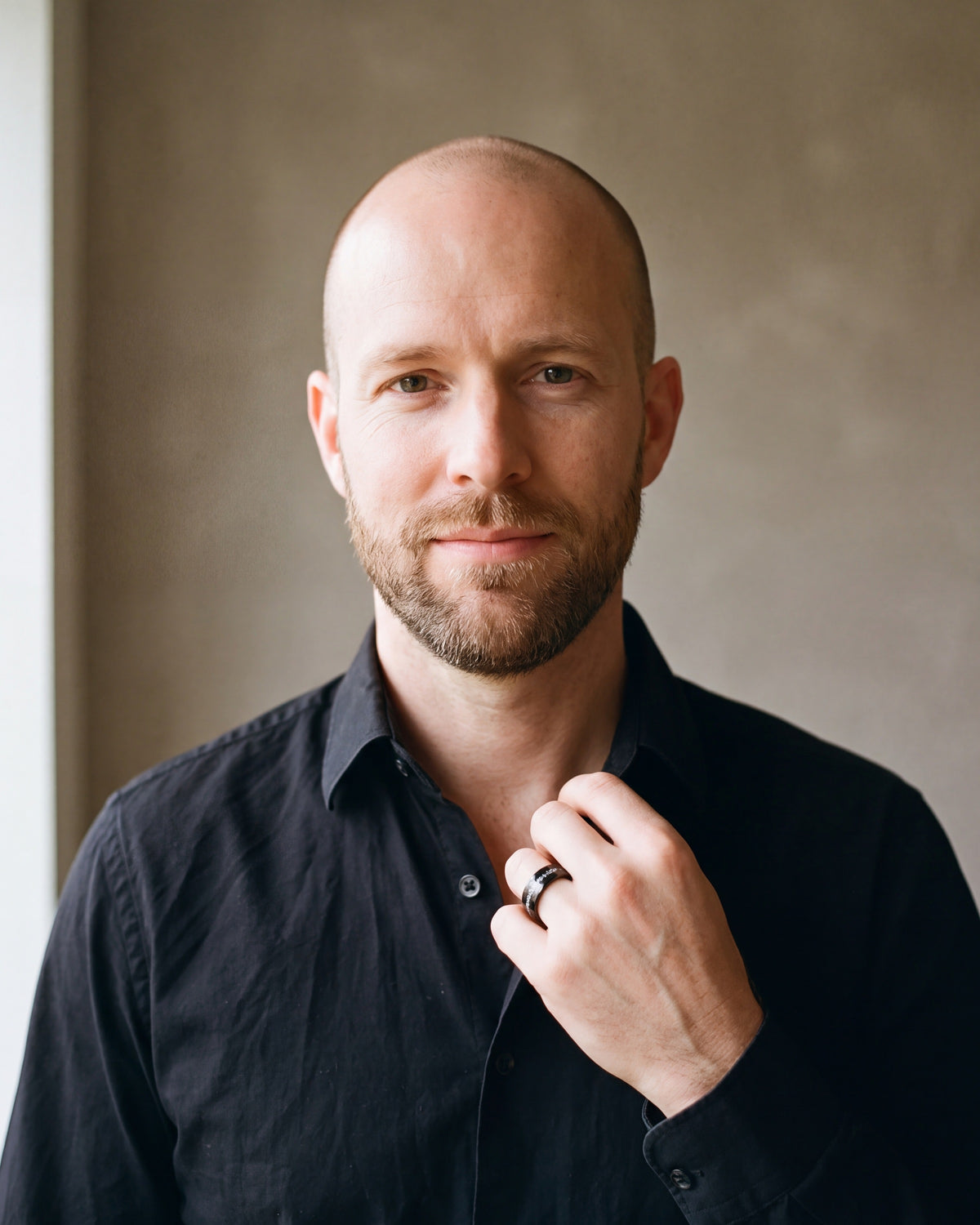 Man in a black shirt by a window wearing the Atlas crushed metal inlay ring in black steel