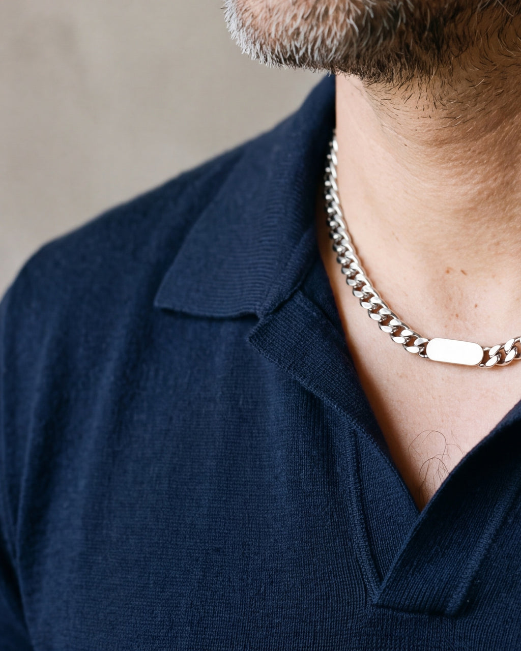 Close-up of the silver Atlas Cuban bar chain worn on a navy knit polo at true size