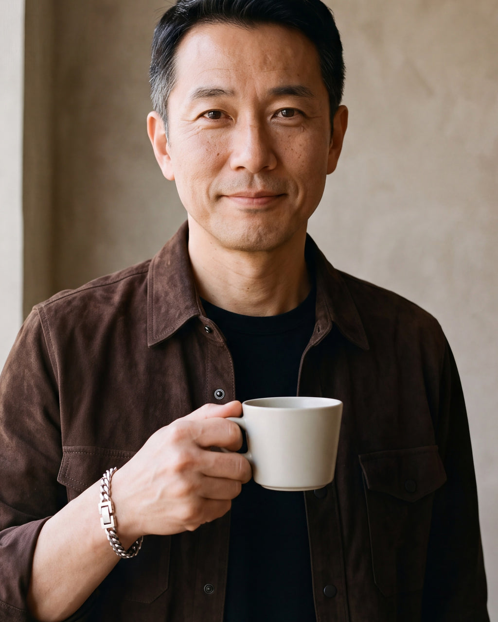 Man in a brown suede overshirt holding a coffee cup, wearing the Atlas classic Cuban bracelet