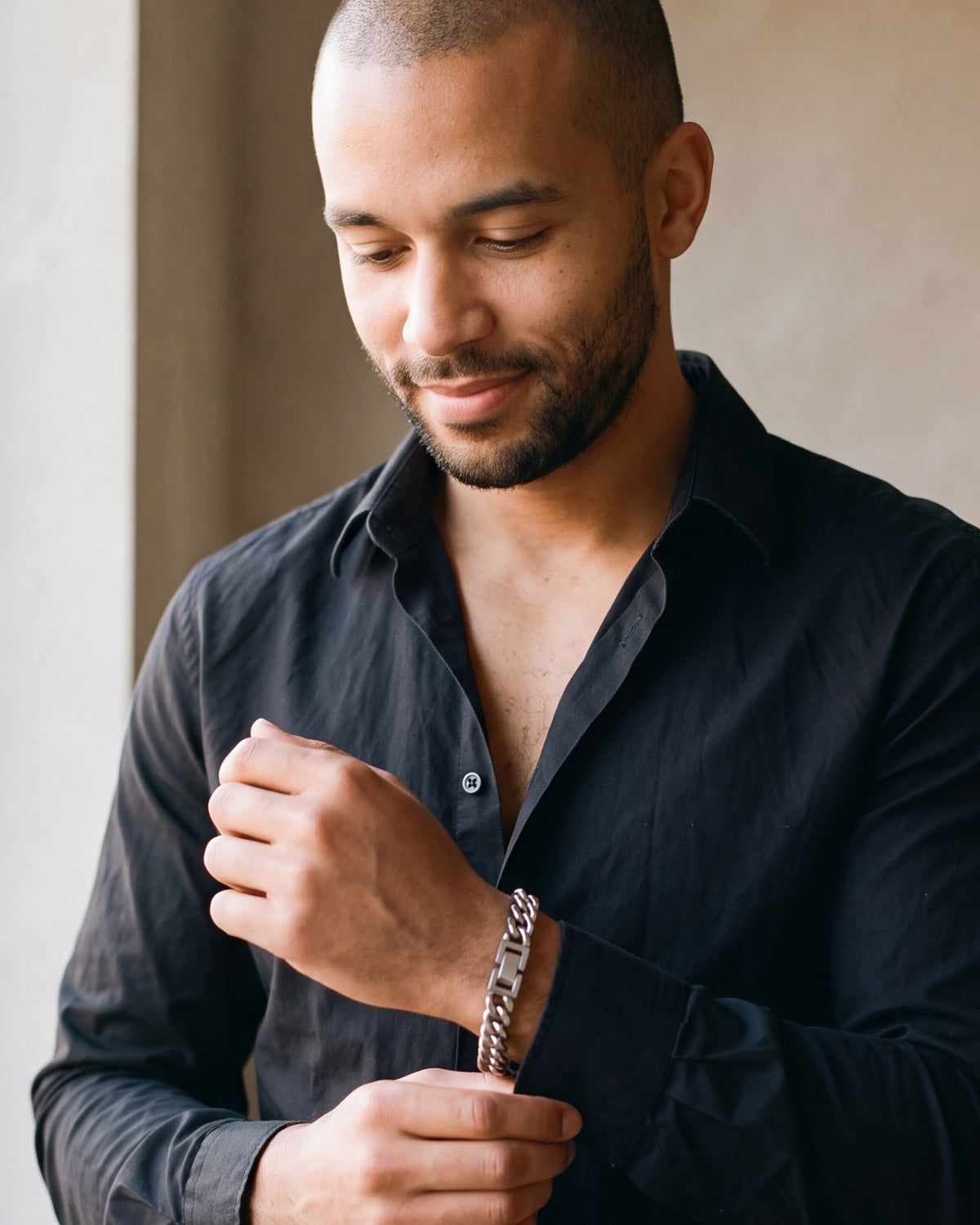 Man in a black shirt adjusting his cuff, wearing the Atlas double Cuban bracelet