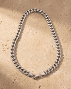 The whole silver Atlas Cuban Chain lying on warm travertine stone