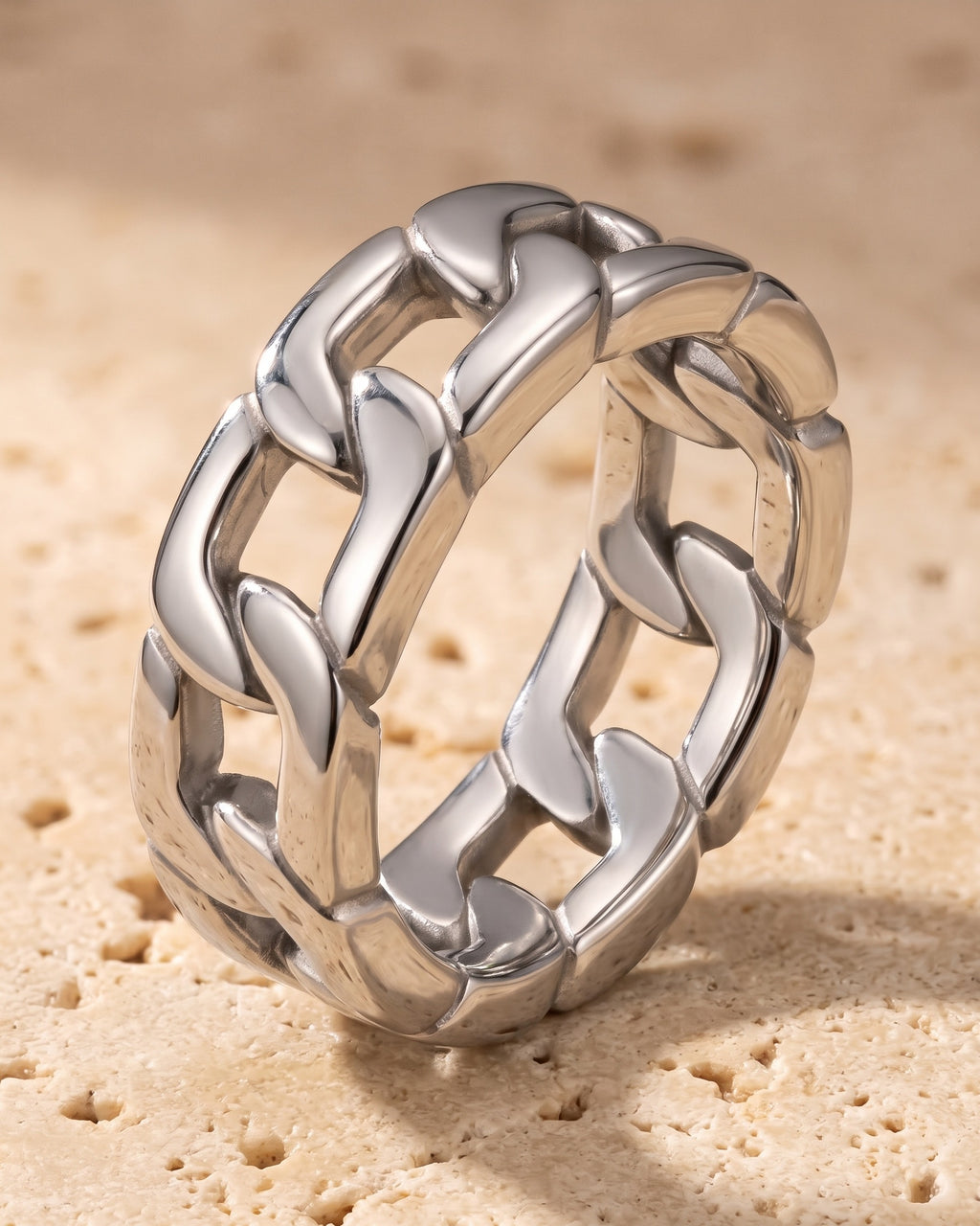 The whole silver-tone Atlas Cuban Chain Ring lying on warm travertine stone
