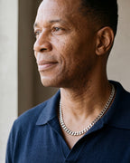 Man in a navy knit polo looking toward the window, wearing the 7 mm Atlas Cuban chain