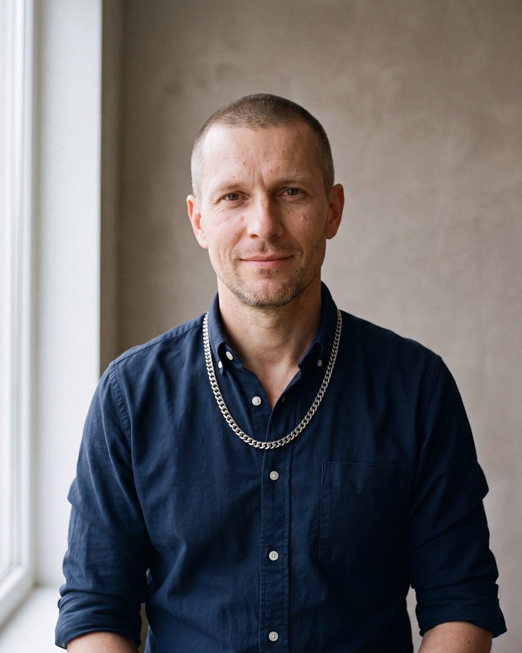 Man in a dark navy cotton oxford shirt by a window wearing the silver Atlas Cuban Chain