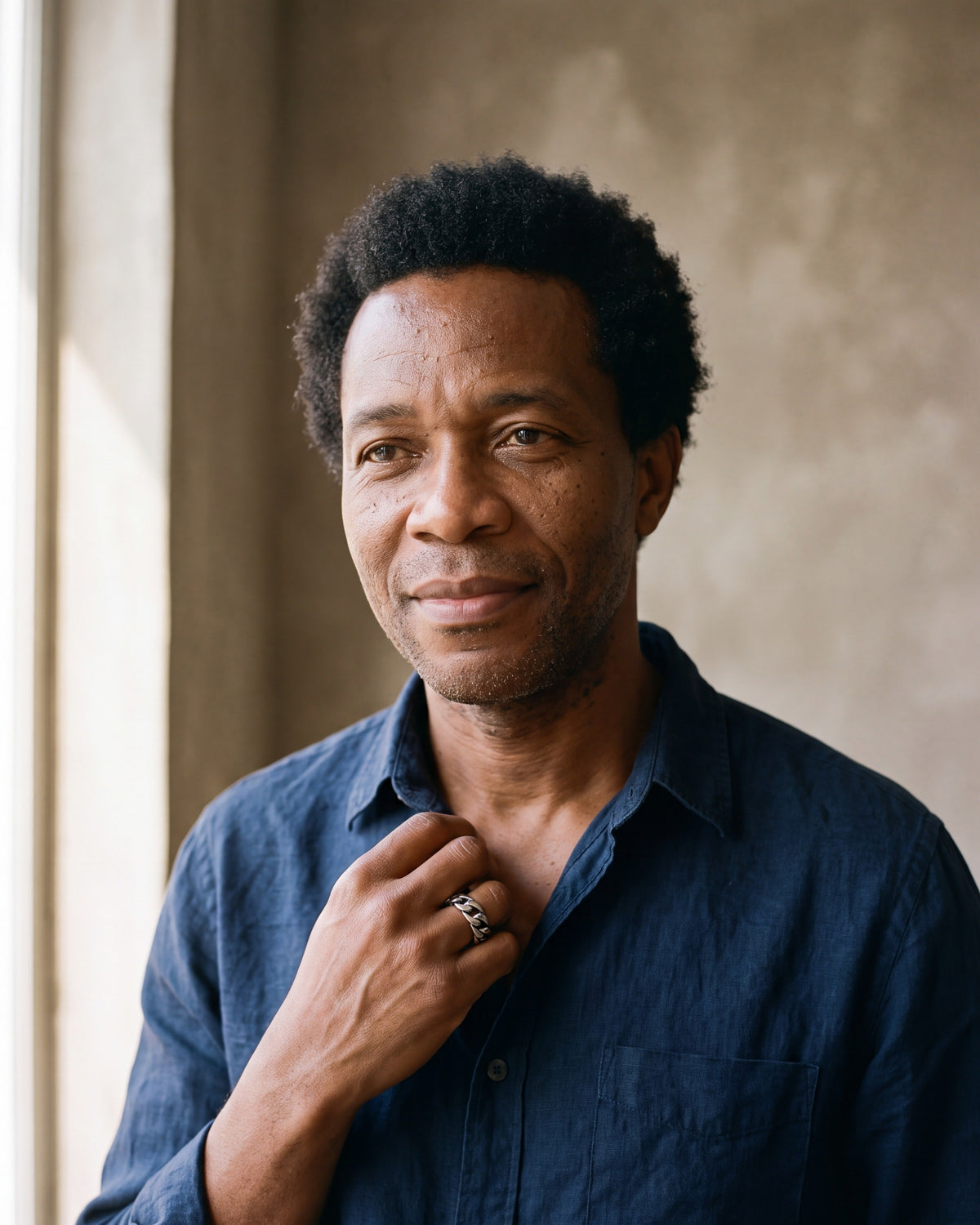 Man in a charcoal henley by a window wearing the Atlas Cuban link band ring in silver-tone steel