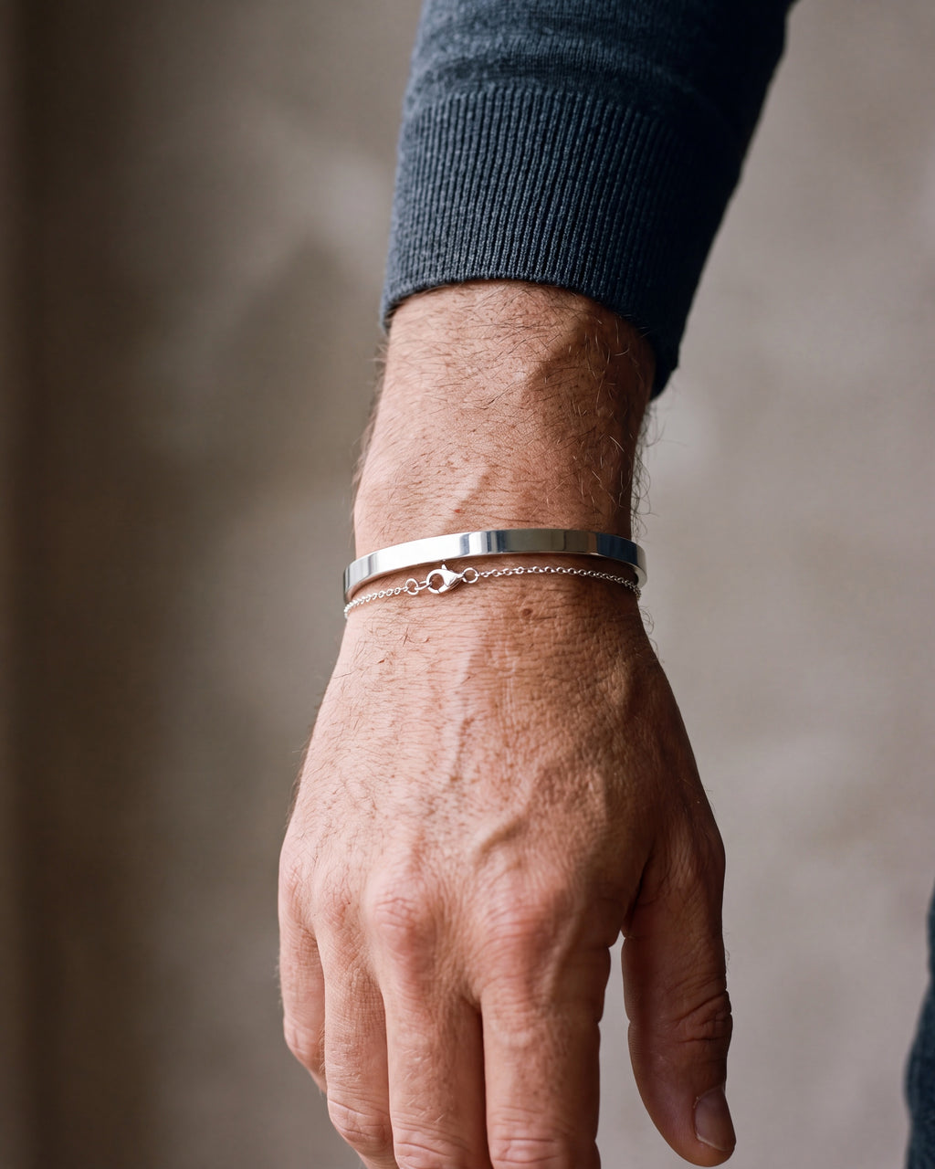 Close-up of the silver-tone Atlas cuff and chain bracelet set worn by a man, shown at true size