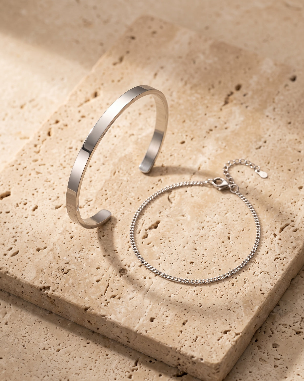 The whole silver-tone Atlas cuff and chain bracelet set laid on warm stone