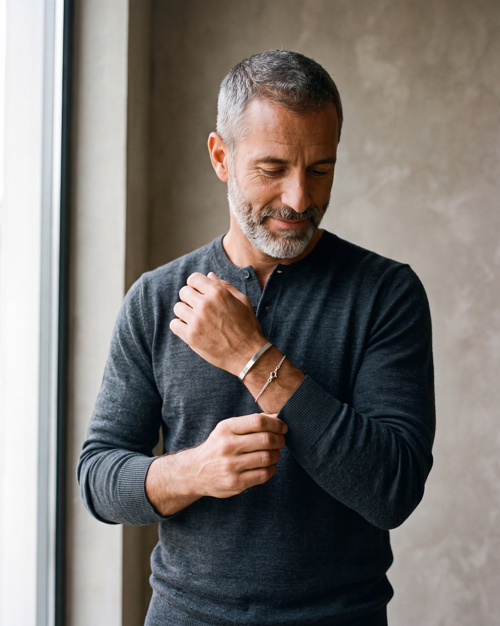 Man in a charcoal knit adjusting his sleeve wearing the silver-tone Atlas cuff and chain bracelet set