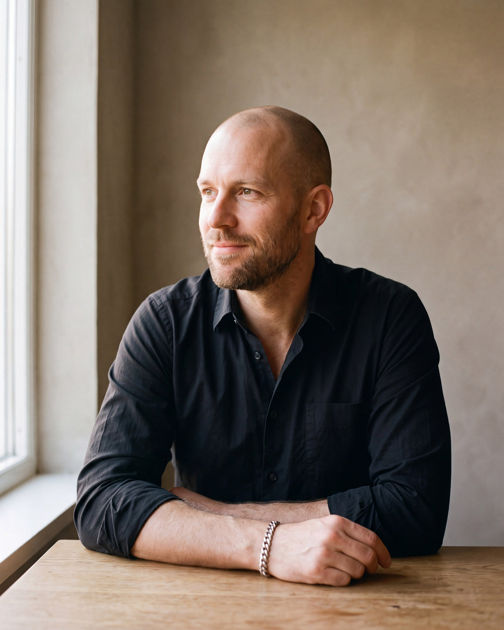 Man in a black shirt by a window wearing the Atlas curb link bracelet in silver-tone steel