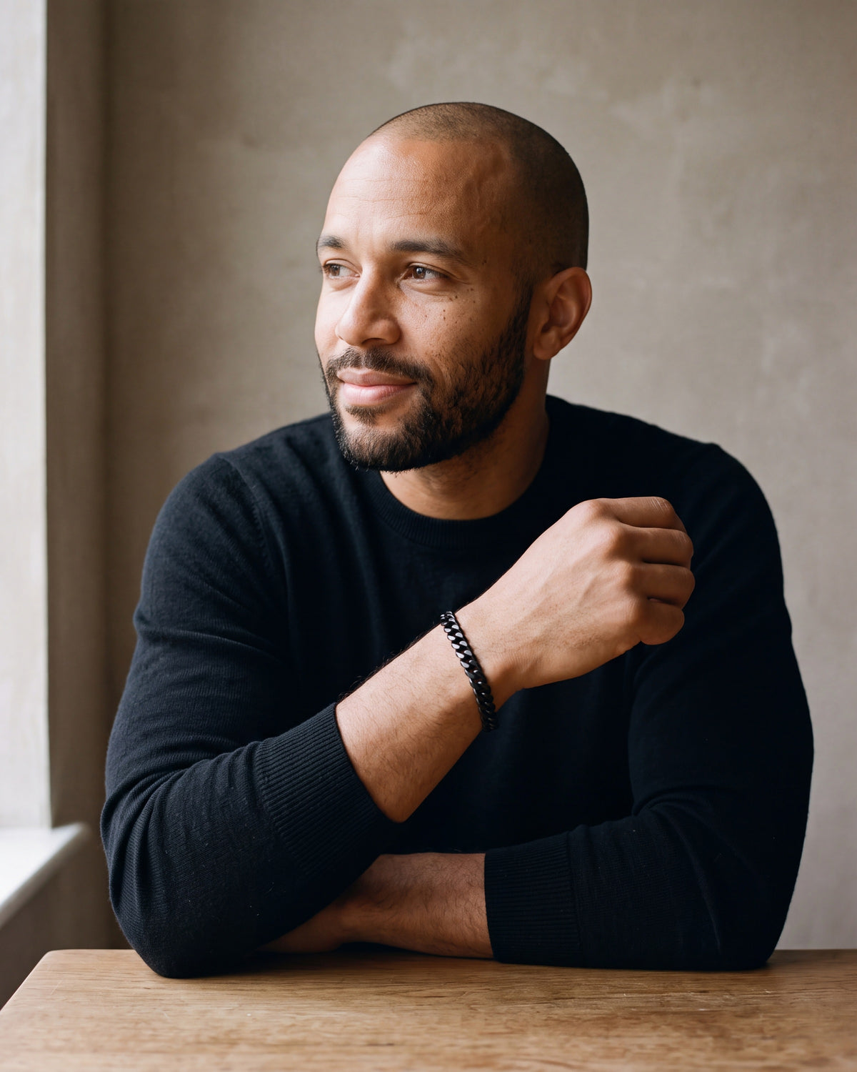 Man in a black merino sweater wearing the Atlas curb link bracelet in black steel