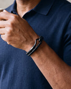 Close-up of the black Atlas curved hook leather bracelet on a man's wrist at true size