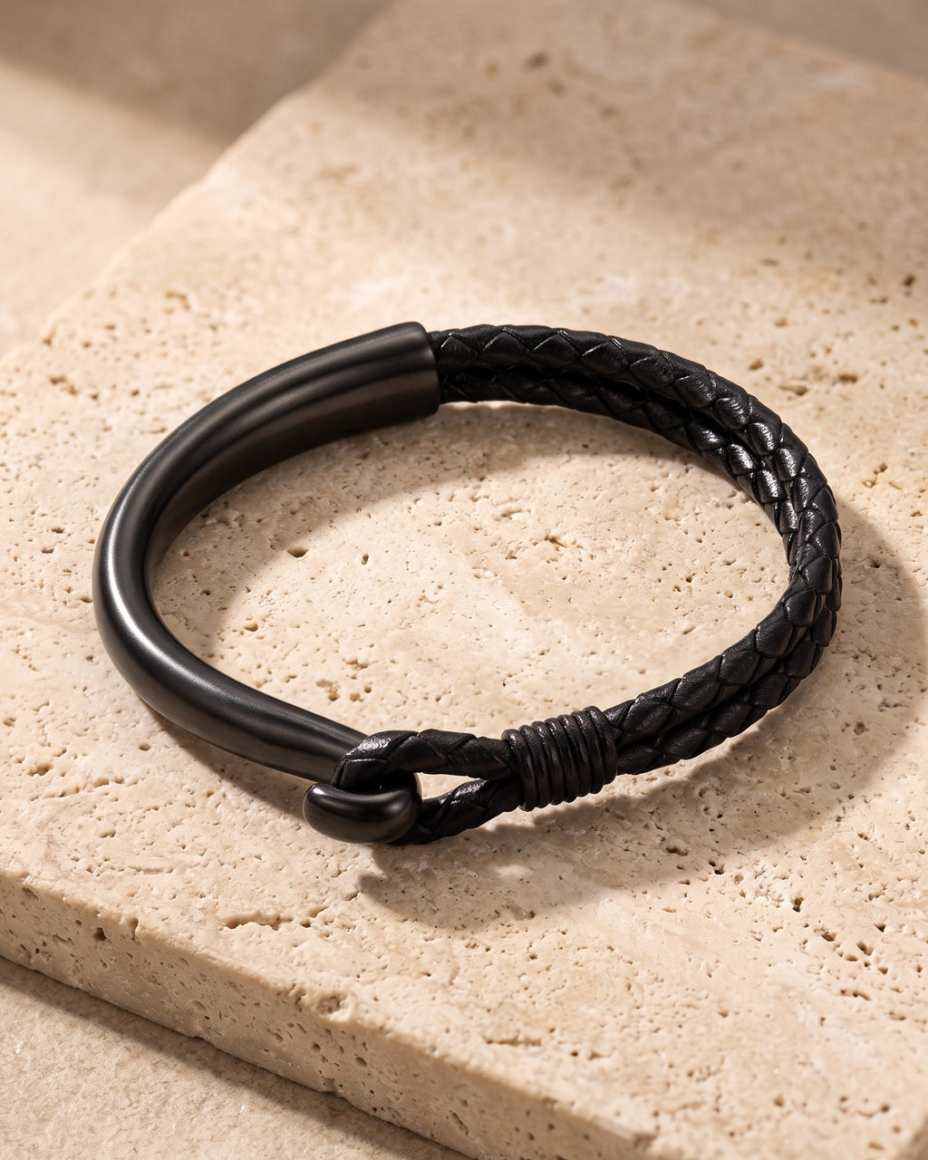 Black Atlas curved hook leather bracelet closed on warm stone