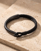 Black Atlas curved hook leather bracelet closed on warm stone