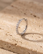 Silver Atlas cubic zirconia hoop earring standing on warm stone