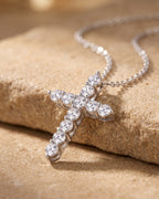 Close-up of the silver Atlas CZ cross pendant on warm stone, prong-set stones