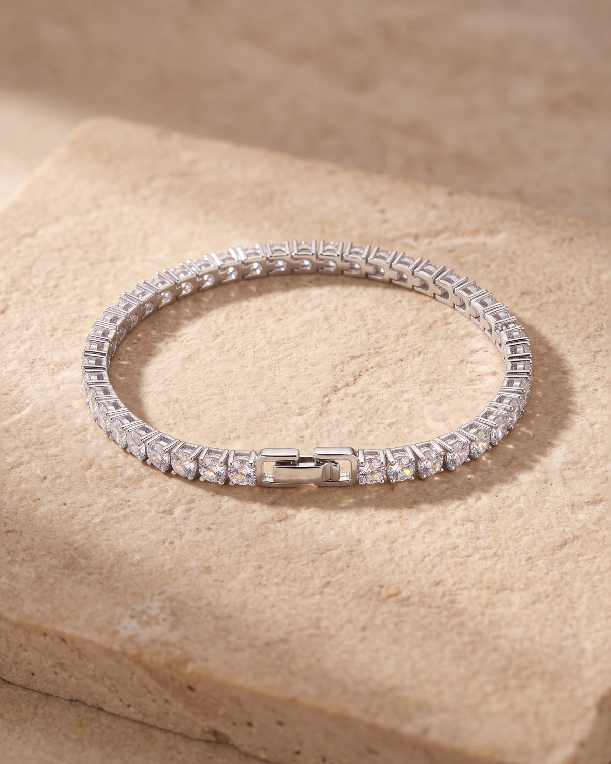 The whole silver Atlas CZ tennis bracelet closed, lying on warm stone