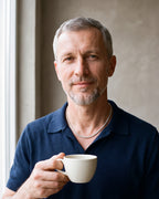 Man in a navy knit polo holding a coffee cup, wearing the silver Atlas 4 mm CZ tennis chain