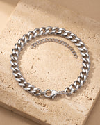 The whole silver-tone Atlas Diamond-Cut Cuban Bracelet lying on warm travertine stone