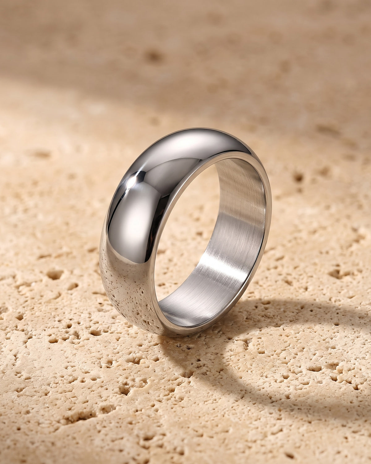 The whole silver-tone Atlas Dome Band lying on warm travertine stone