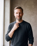 Man in a charcoal fine-gauge knit crew-neck sweater by a window wearing the silver-tone Atlas Dome Band
