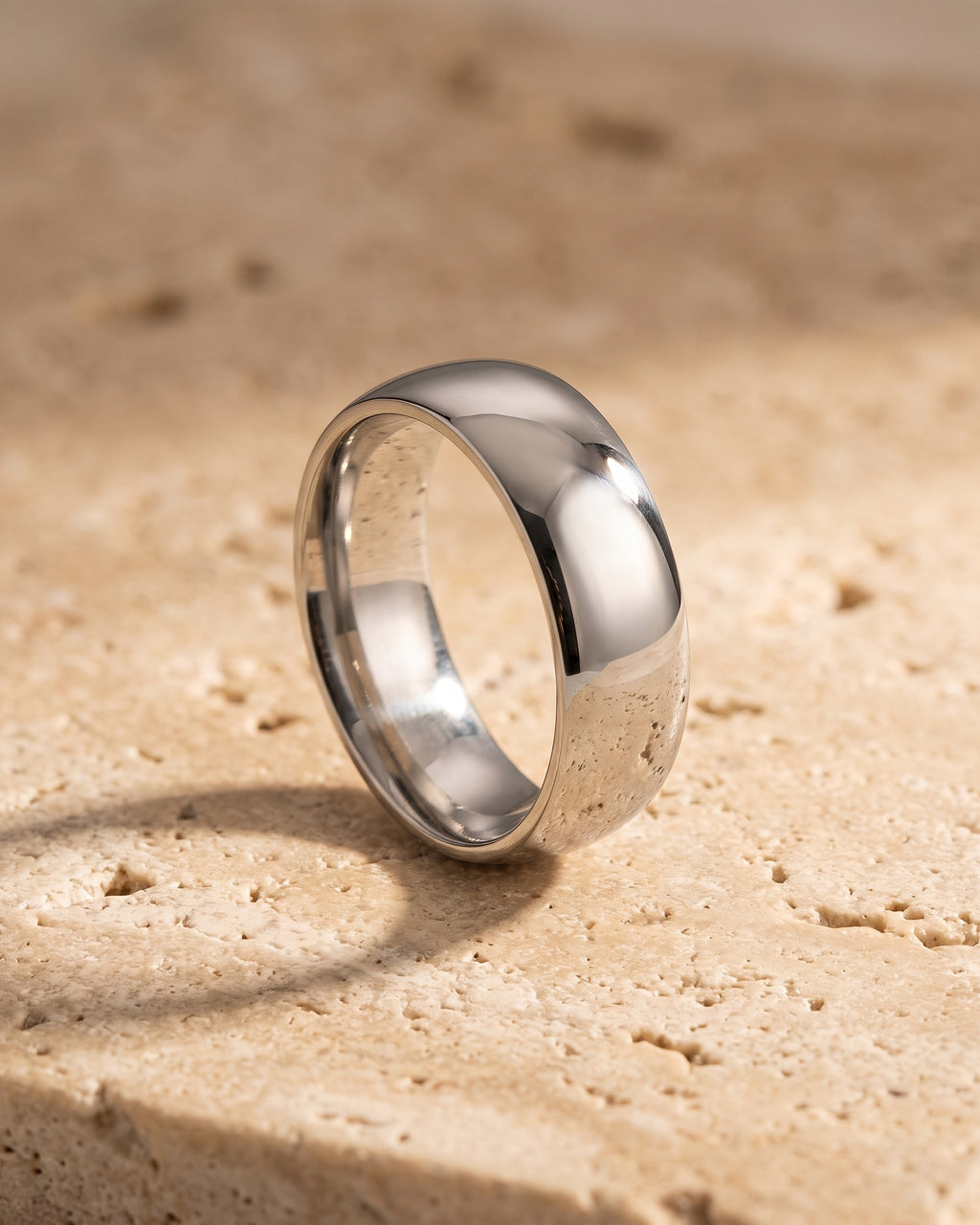Entire Atlas domed band in silver-tone steel, lying flat on warm stone