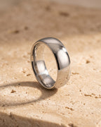 Entire Atlas domed band in silver-tone steel, lying flat on warm stone