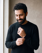 Man in a black sweater adjusting his cuff, wearing the black Atlas domed tungsten ring