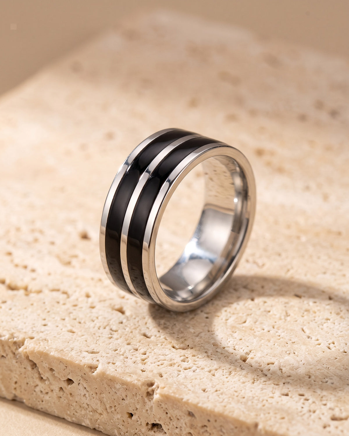 The Atlas double black inlay ring standing on warm stone