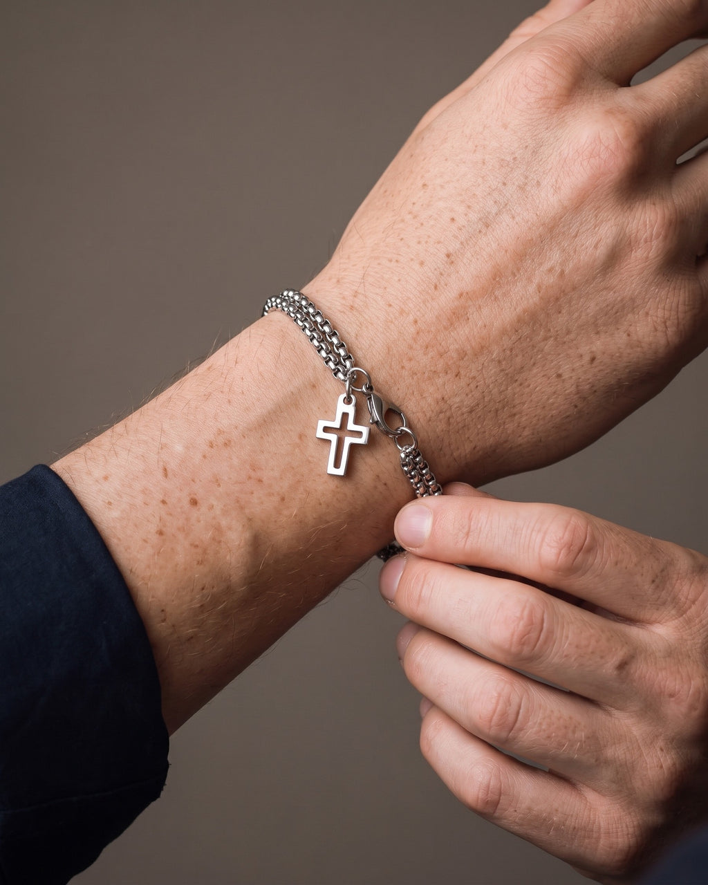 Hand adjusting the Atlas Double Rolo Chain Cross Bracelet on the wrist