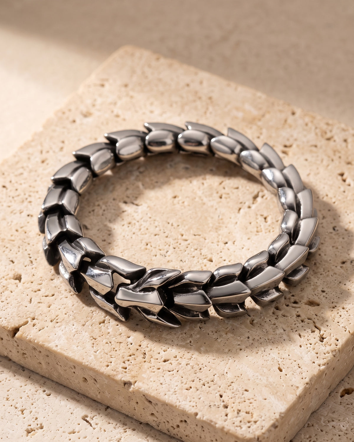The whole silver Atlas dragon scale bracelet closed on warm stone, dragon head clasp