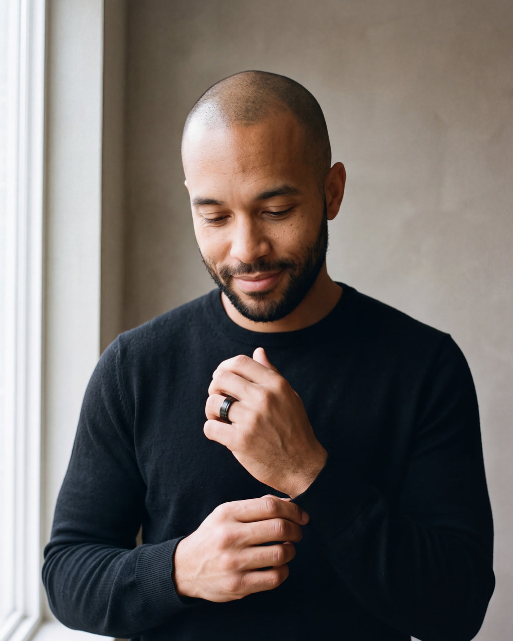 Man in a black merino sweater by a window wearing the Atlas dual groove ring in black steel