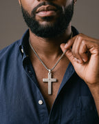 Hand lifting the Atlas Engraved Cross Necklace in Titanium Steel at the collarbone