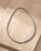 Silver Atlas rope chain laid whole on warm stone, lobster clasp closed