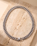 The whole silver-tone Atlas faceted double-link cuban chain lying on warm travertine stone