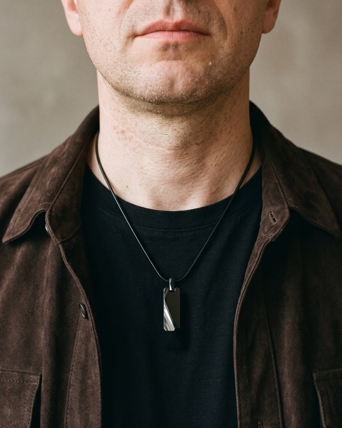 Atlas faceted pendant necklace in black tungsten carbide worn on the chest, close-up
