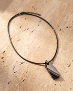 Black Atlas faceted tungsten pendant and snake chain on warm stone