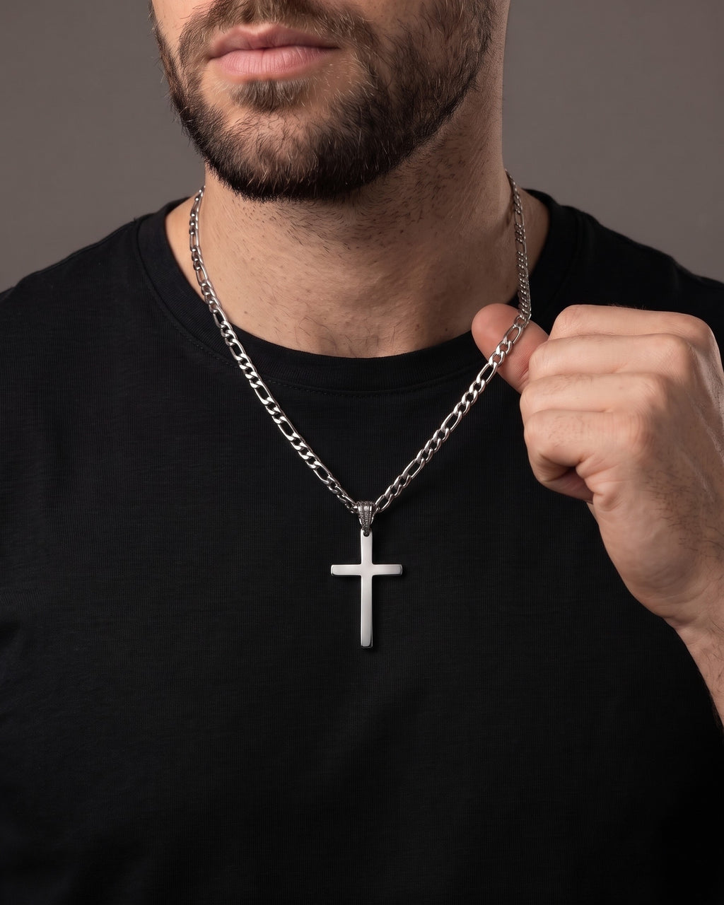 Hand lifting the Atlas Figaro Chain Cross Necklace in Titanium Steel at the collarbone