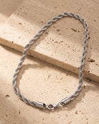 The whole silver Atlas fine rope chain lying on warm travertine stone