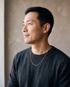 Man in a charcoal fine-gauge knit crew-neck sweater wearing the gold-tone Atlas Fine Snake Chain