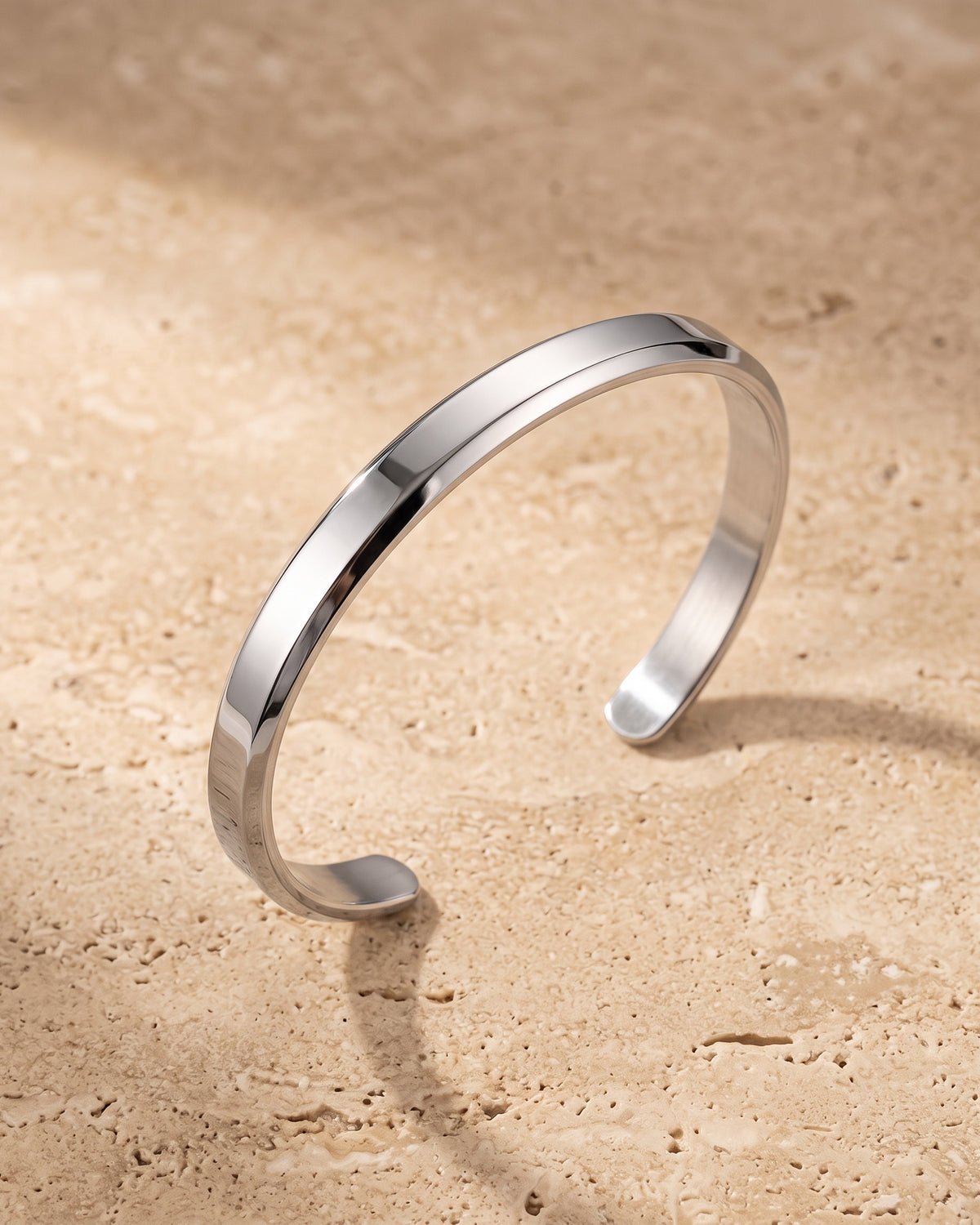 Silver Atlas flat cuff bracelet on warm stone