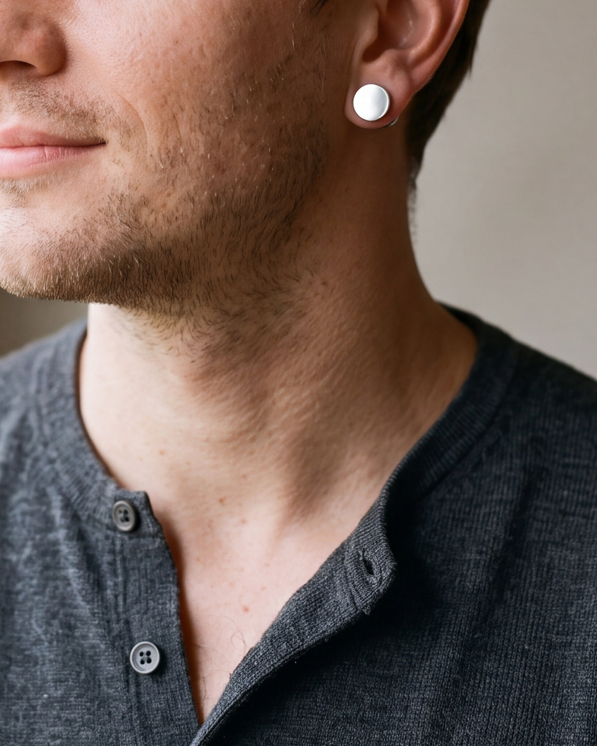 Close-up of the Atlas flat disc barbell stud earrings in silver-tone steel, worn at true size