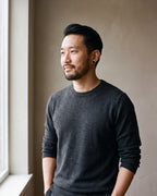 Man in a charcoal sweater with his hands in his pockets wearing the black Atlas flat disc stud earrings