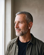 Man in an olive overshirt seen in profile wearing the silver-tone Atlas flat disc stud earrings