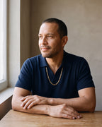 Man in a navy fine-gauge knit polo with an open collar wearing the gold-tone Atlas Flat Gold-Tone Figaro Chain