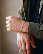 Close-up of the silver-tone Atlas flat link chain worn by a man, shown at true size